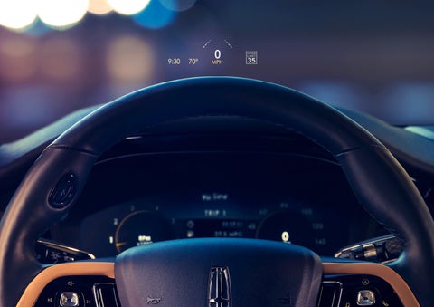 The available head-up display projects data on the windshield above the steering wheel inside a 2022 Lincoln Corsair as the driver navigates the city at night | Evergreen Lincoln in Issaquah WA