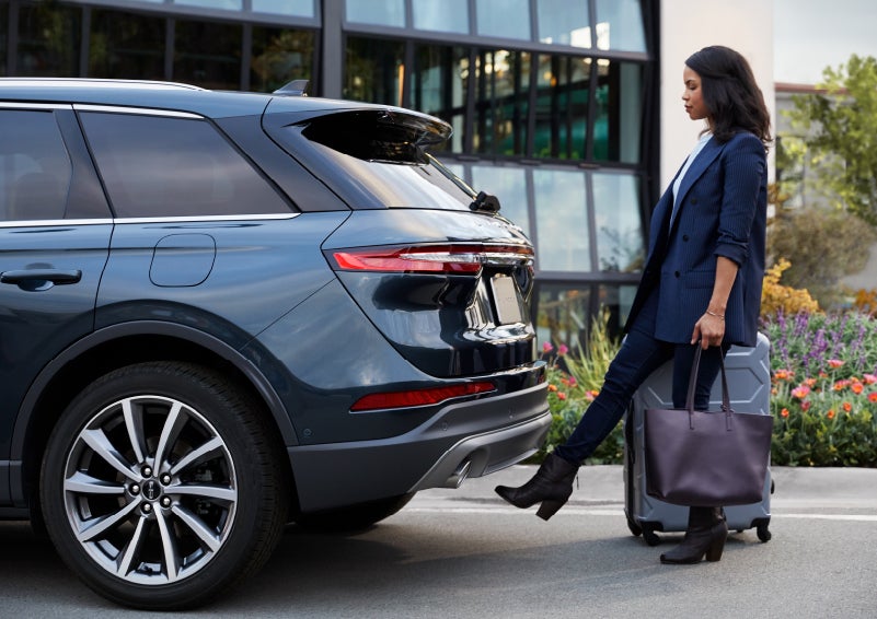 A woman with luggage and a bag opens the available hands-free liftgate by kicking her foot under the bumper | Evergreen Lincoln in Issaquah WA