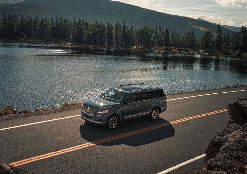 A 2023 Lincoln Navigator SUV is being driven on a lakeside road. | Evergreen Lincoln in Issaquah WA